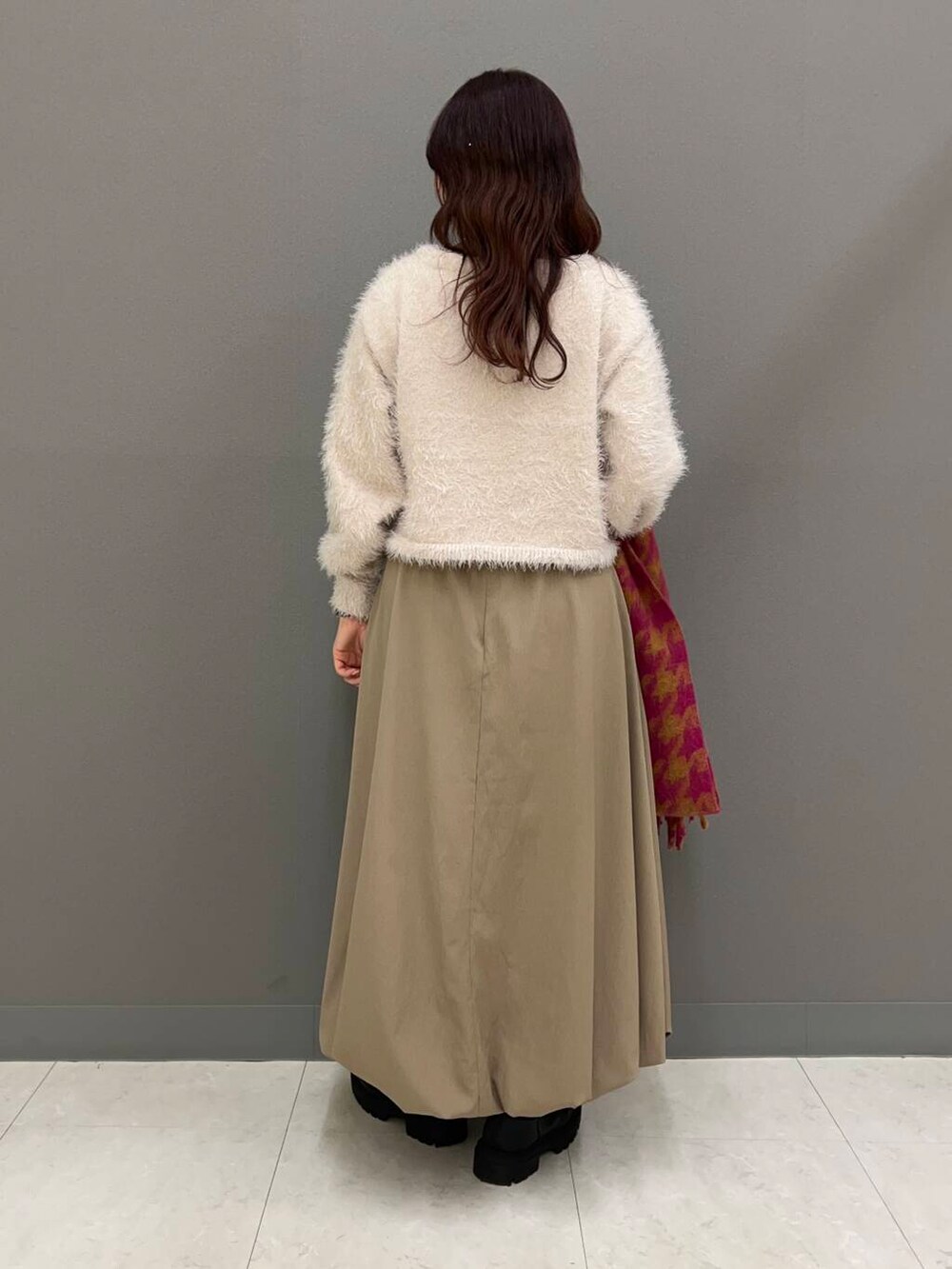 ブラック系のブーツ、ベージュ系のニット/セーター、ベージュ系のスカートを着用したレディースの冬コーディネートの3枚目の写真