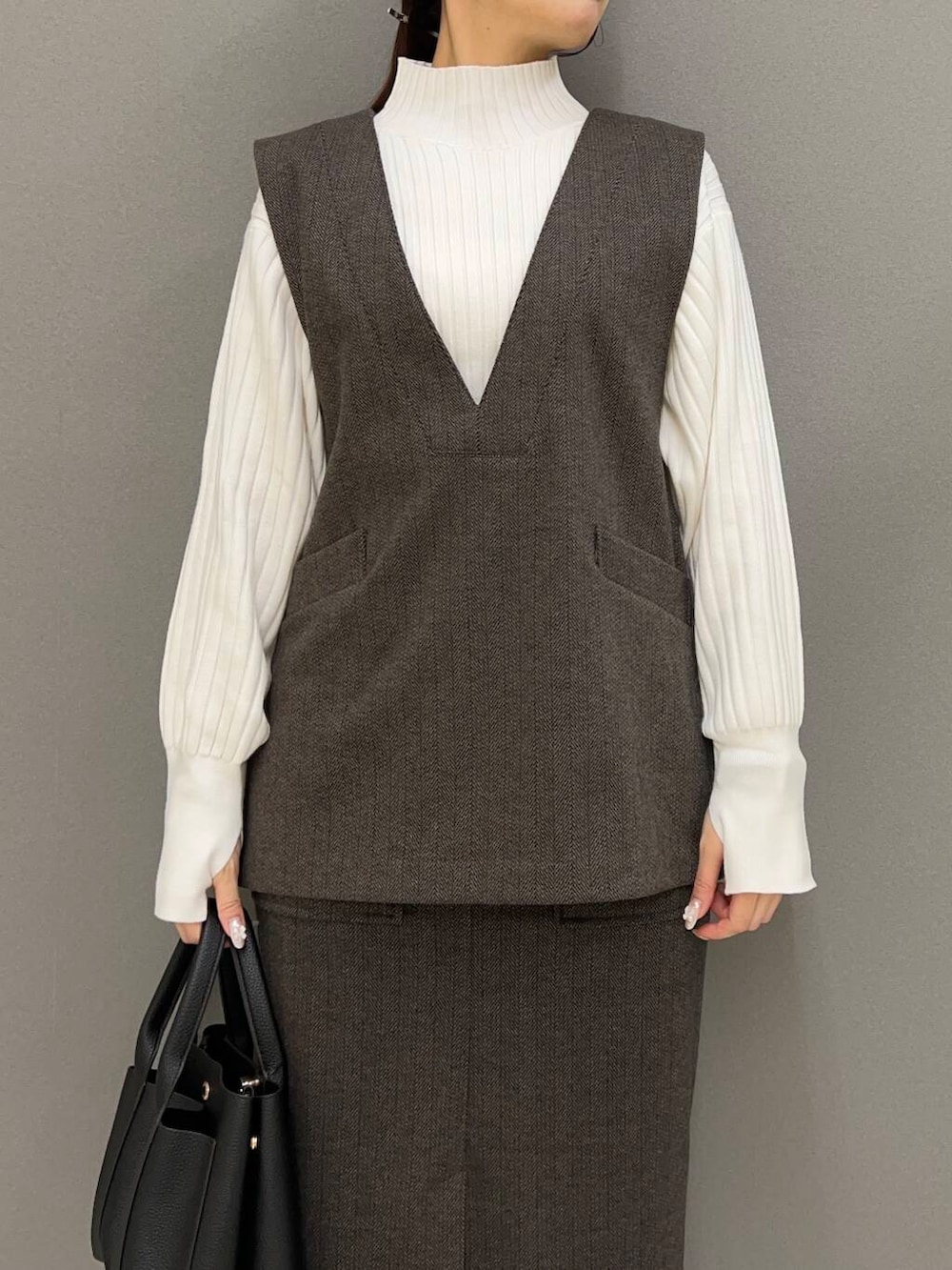 ブラック系のブーツ、ブラウン系のスカート、ブラウン系のベストを着用したレディースの冬コーディネートの2枚目の写真