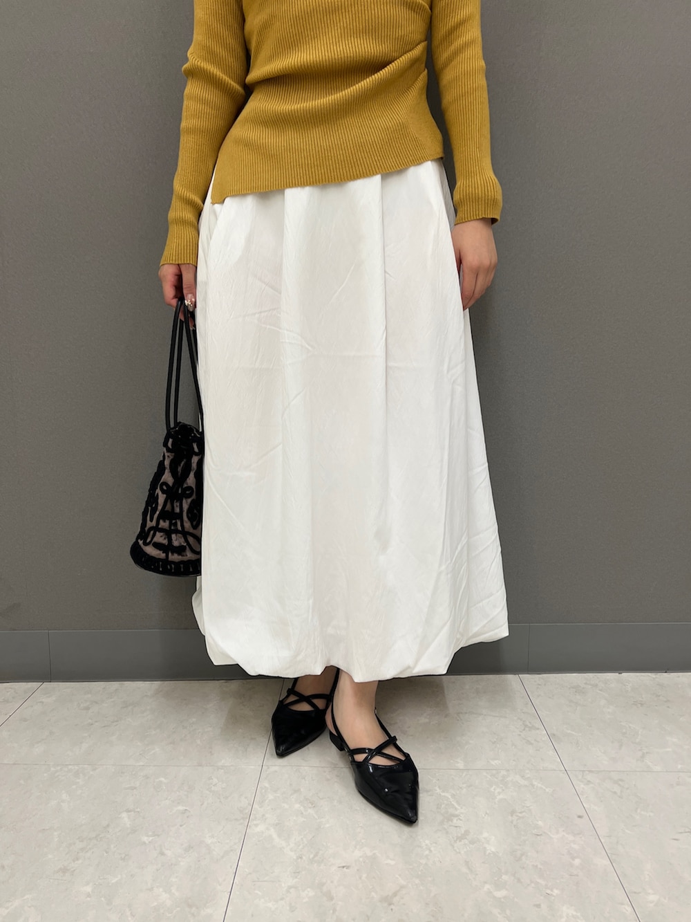 イエロー系のニット/セーター、ホワイト系のスカート、ブラック系のその他シューズを着用したレディースの秋コーディネートの3枚目の写真