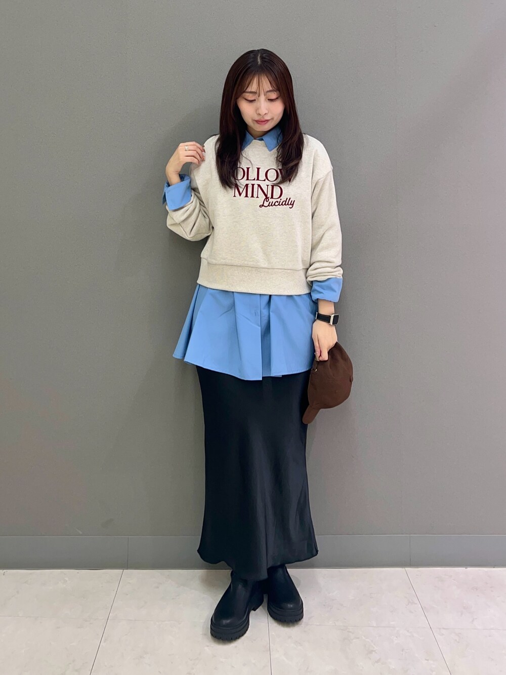 ベージュ系のスウェット、ブルー系のシャツ/ブラウス、ブラック系のスカートを着用したレディースの秋コーディネートの2枚目の写真