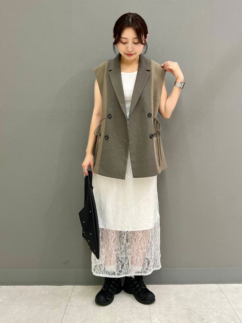 ブラック系のトートバッグ、ホワイト系のTシャツ/カットソー、ブラウン系のベストを着用したレディースの秋コーディネートの2枚目の写真