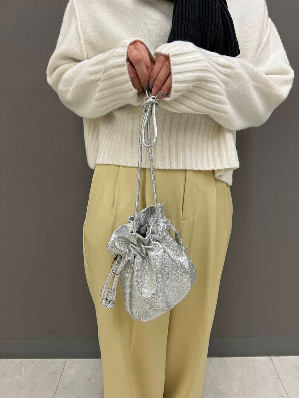 シルバー系のショルダーバッグ、イエロー系のその他パンツ、ホワイト系のニット/セーターを着用したレディースの冬コーディネートの4枚目の写真