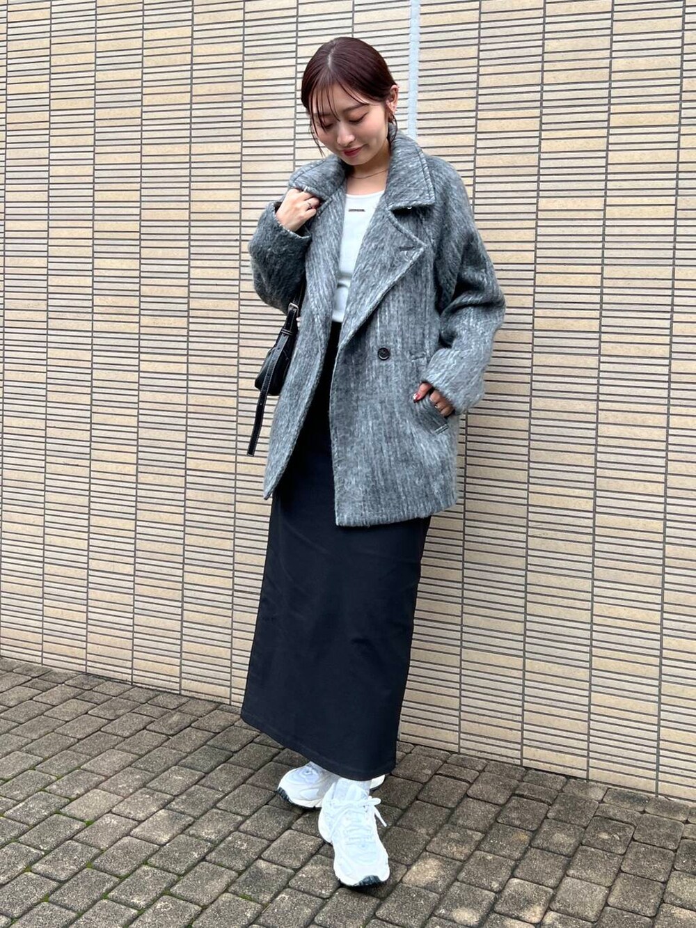 ブラック系のスカート、グレー系のショルダーバッグ、ホワイト系のTシャツ/カットソーを着用したレディースの秋コーディネートの2枚目の写真