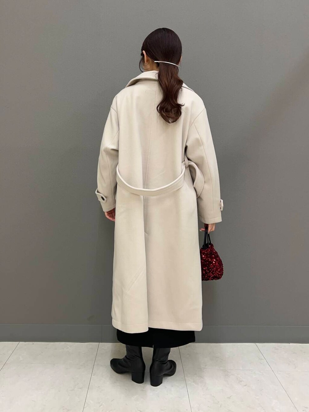 ブラック系のブーツ、ベージュ系のその他アウター、レッド系のショルダーバッグを着用したレディースの冬コーディネートの3枚目の写真