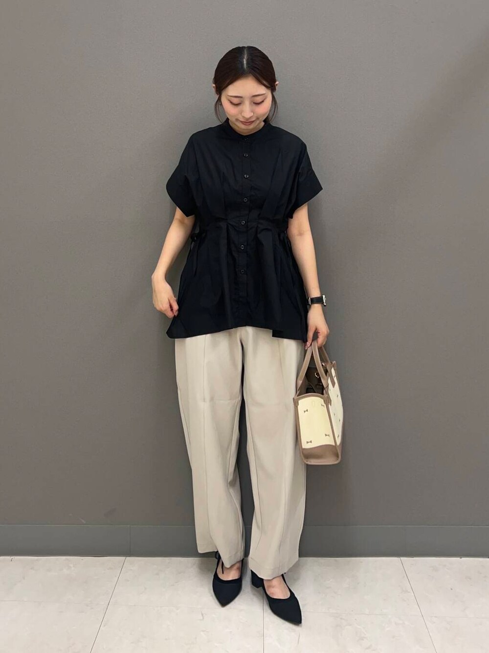ブラック系のパンプス、ブラック系のシャツ/ブラウス、ベージュ系のハンドバッグを着用したレディースの夏コーディネートの2枚目の写真