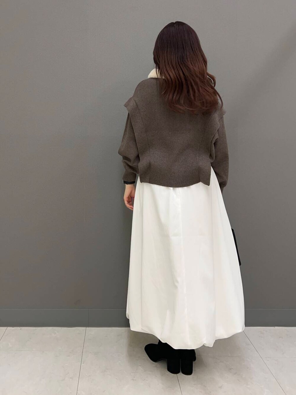 ブラック系のブーツ、ブラック系のハンドバッグ、ブラウン系のニット/セーターを着用したレディースの冬コーディネートの2枚目の写真