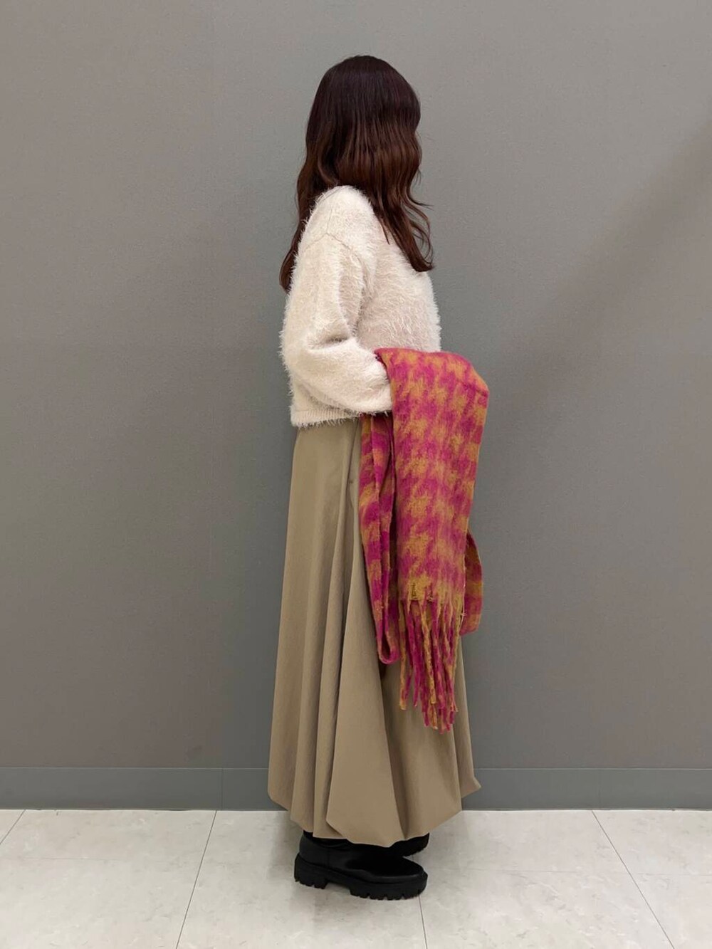 ブラック系のブーツ、ベージュ系のニット/セーター、ベージュ系のスカートを着用したレディースの冬コーディネートの2枚目の写真