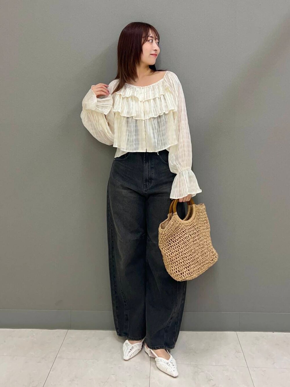 ベージュ系のトートバッグ、ホワイト系のサンダル、グレー系のデニムパンツを着用したレディースの春コーディネートの2枚目の写真