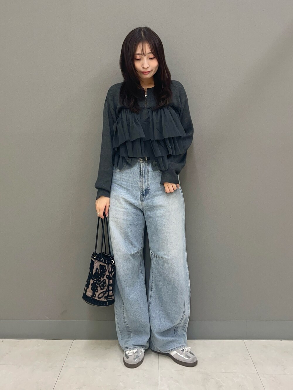 ブルー系のデニムパンツ、ブラウン系のハンドバッグ、グレー系のニット/セーターを着用したレディースの秋コーディネートの2枚目の写真