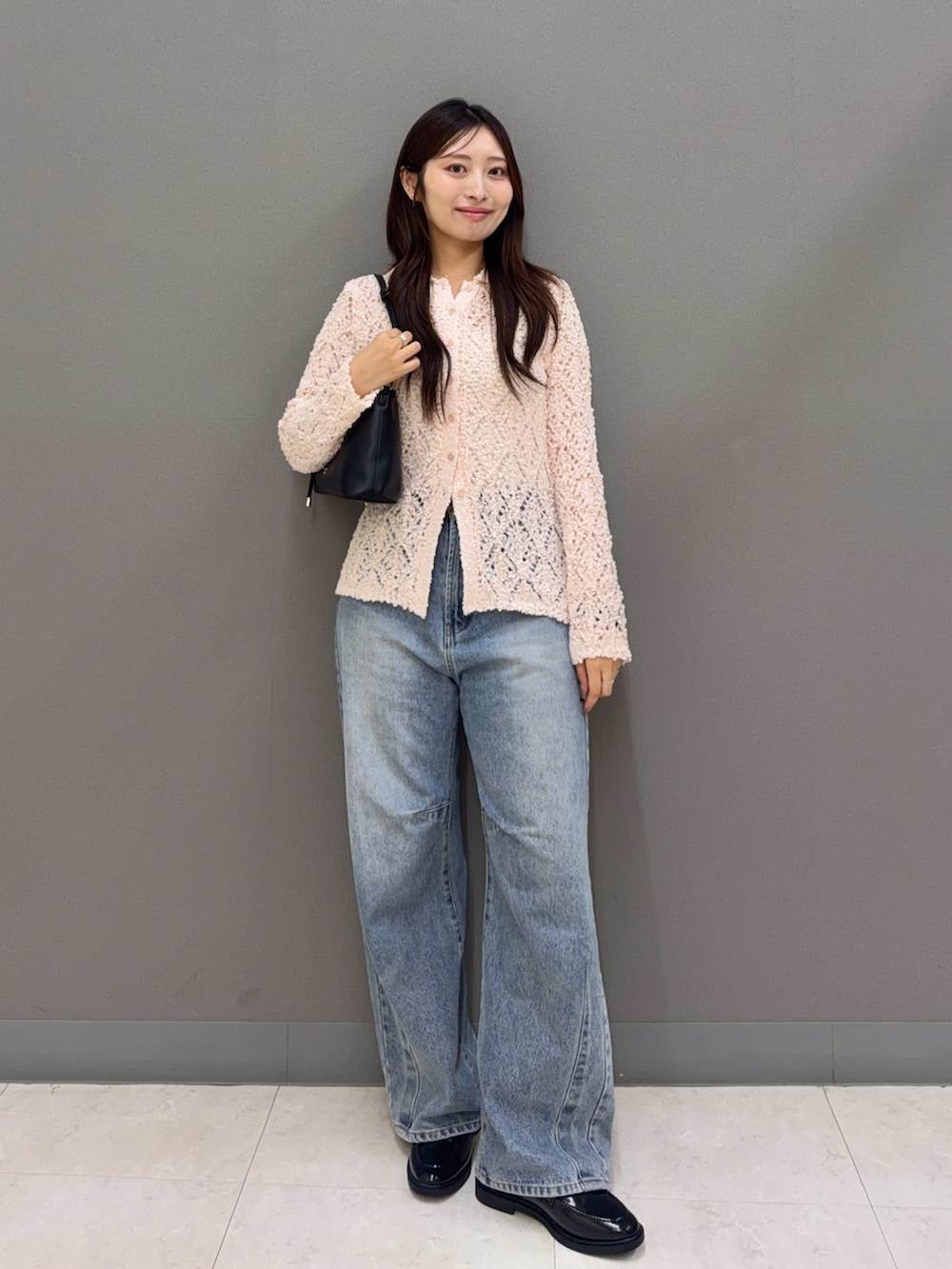 ピンク系のニット/セーター、ブルー系のデニムパンツ、ブラック系のハンドバッグを着用したレディースの秋コーディネートの2枚目の写真