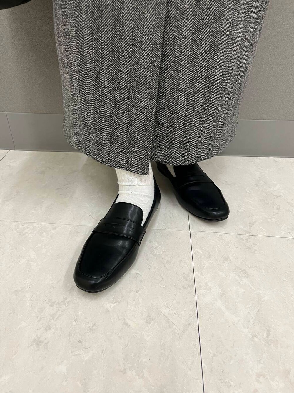 ホワイト系のTシャツ/カットソー、ブラック系のハンドバッグ、ブラック系のローファーを着用したレディースの冬コーディネートの4枚目の写真