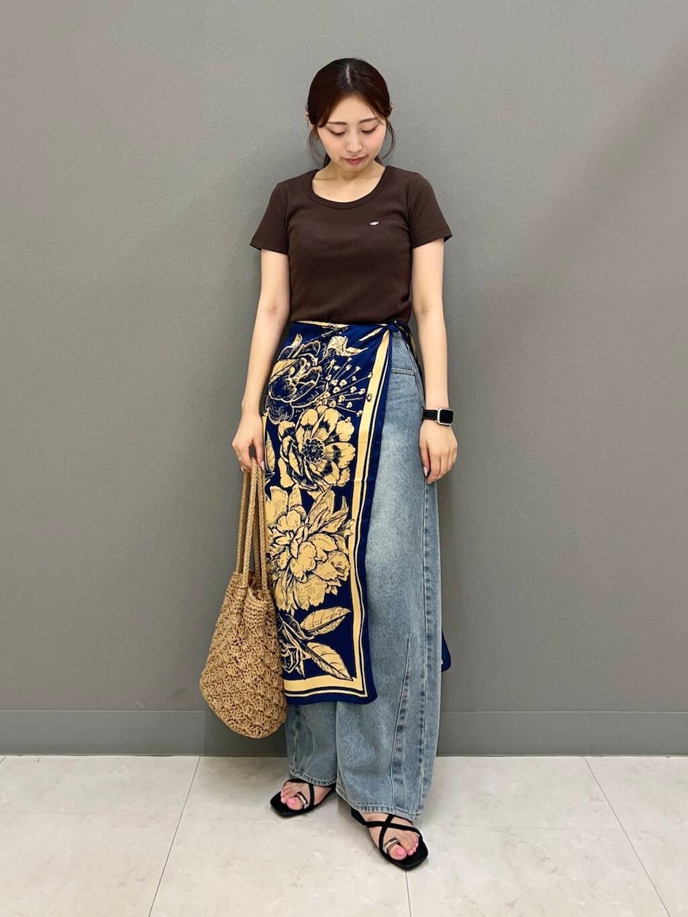 ベージュ系のトートバッグ、ブルー系のデニムパンツ、ブラック系のサンダルを着用したレディースの夏コーディネートの2枚目の写真