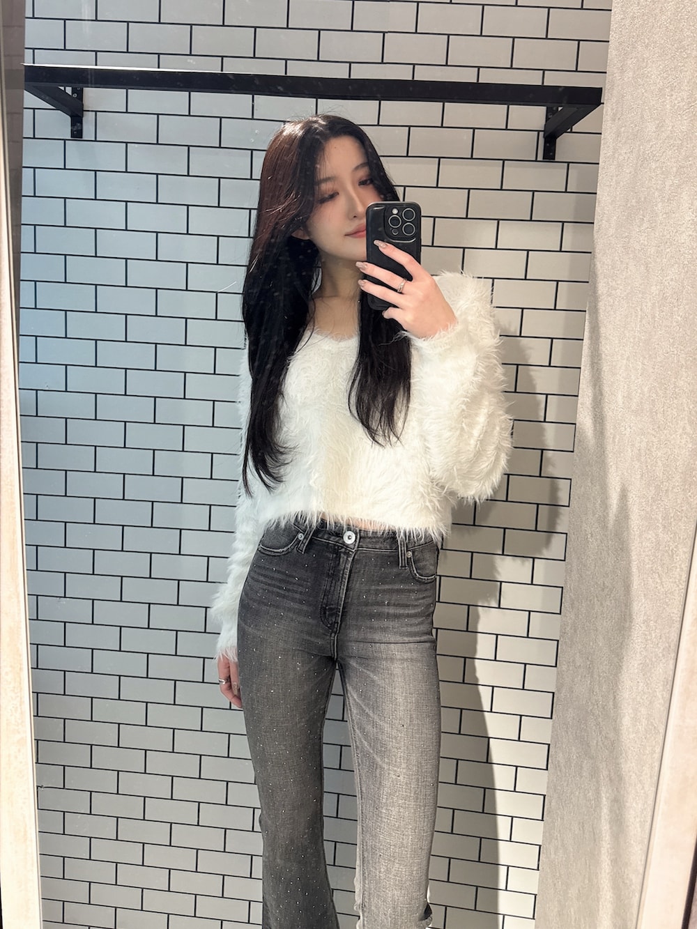 ホワイト系のニット/セーター、ブラック系のデニムパンツ、ブラック系のブーツを着用したレディースの冬コーディネートの3枚目の写真