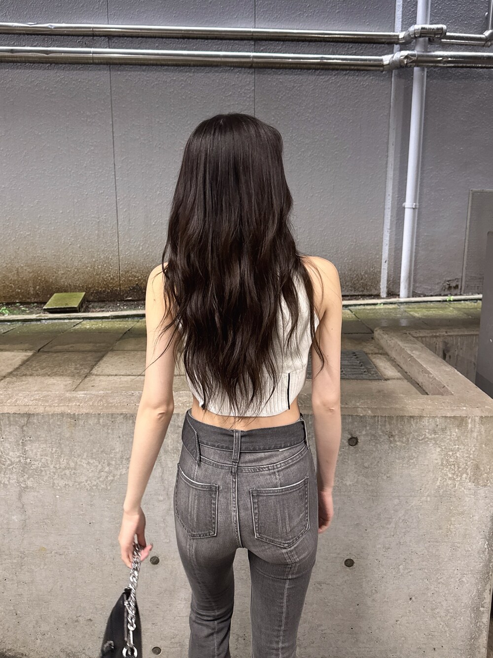 ホワイト系のニット/セーター、ブラック系のデニムパンツ、ブラック系のサンダルを着用したレディースの夏コーディネートの4枚目の写真