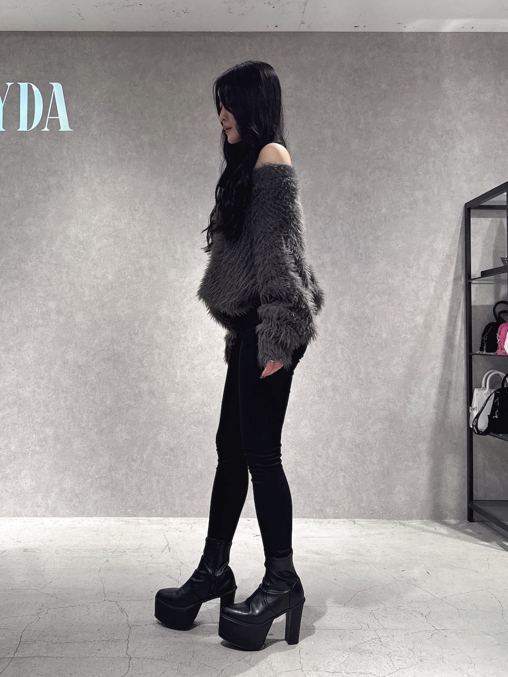 グレー系のニット/セーター、ブラック系のデニムパンツ、ブラック系のブーツを着用したレディースの秋コーディネートの2枚目の写真