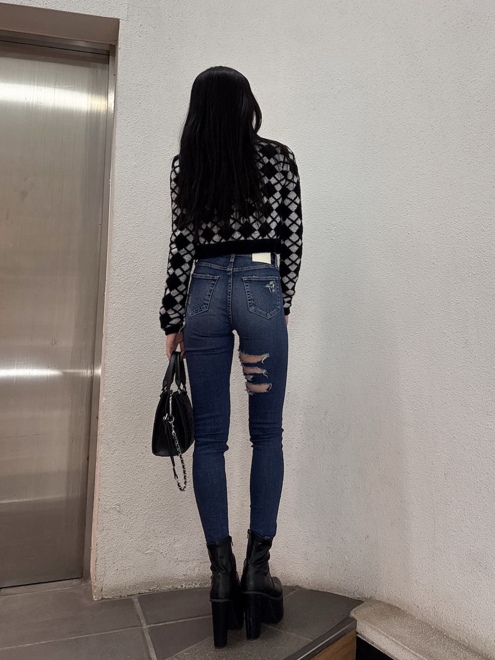 ブラック系のキャミソール、ブラック系のカーディガン/ボレロ、ブルー系のデニムパンツを着用したレディースの冬コーディネートの3枚目の写真