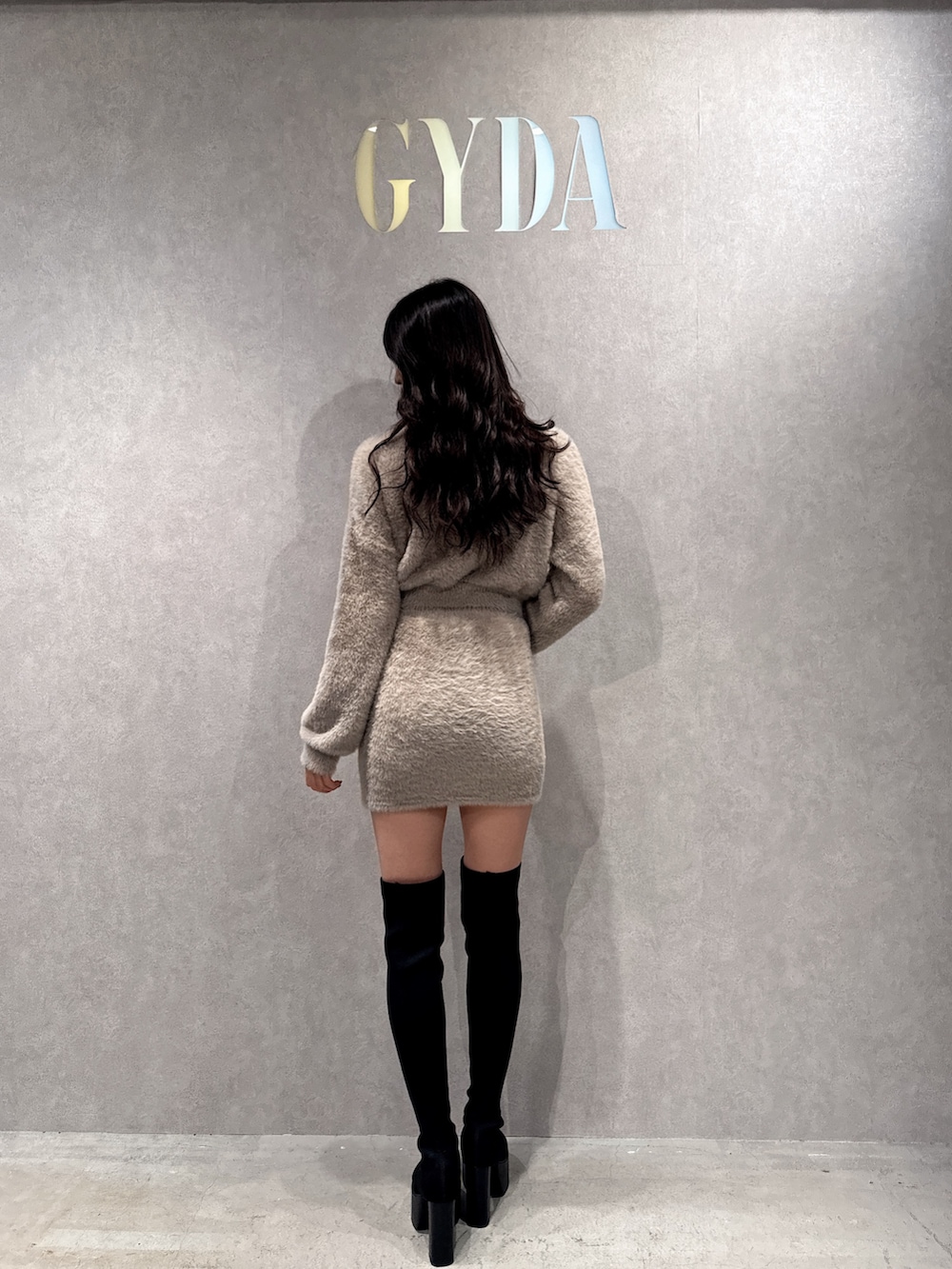 ベージュ系のニット/セーター、ベージュ系のスカート、ブラック系のブーツを着用したレディースの冬コーディネートの2枚目の写真