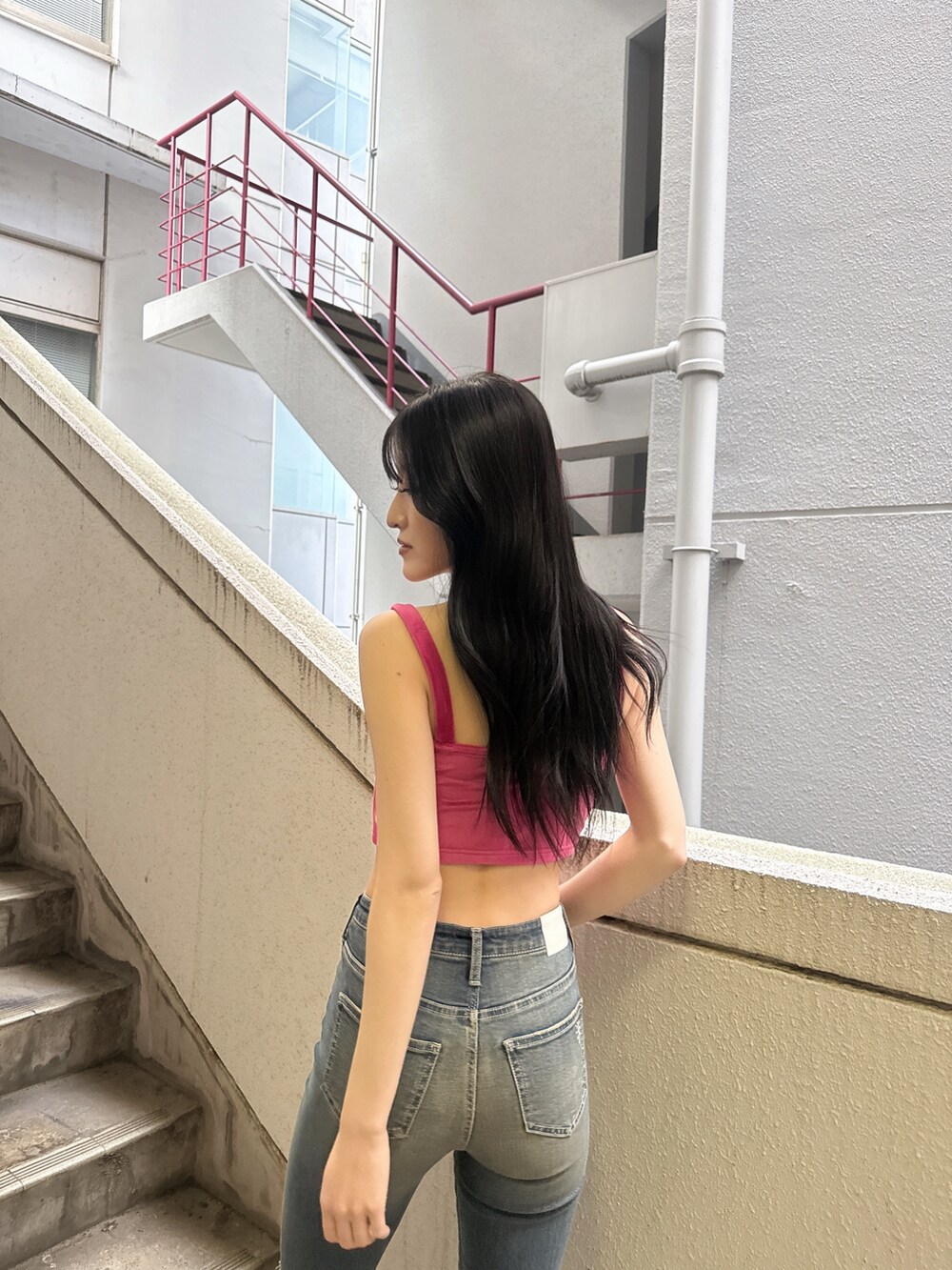 ピンク系のキャミソール、ブルー系のデニムパンツ、ホワイト系のパンプスを着用したレディースの夏コーディネートの3枚目の写真