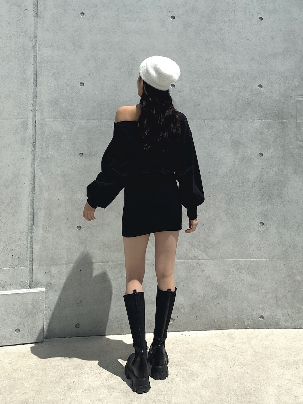 ブラック系のワンピース、ブラック系のブーツ、ホワイト系のニットキャップ/ビーニーを着用したレディースの秋コーディネートの2枚目の写真