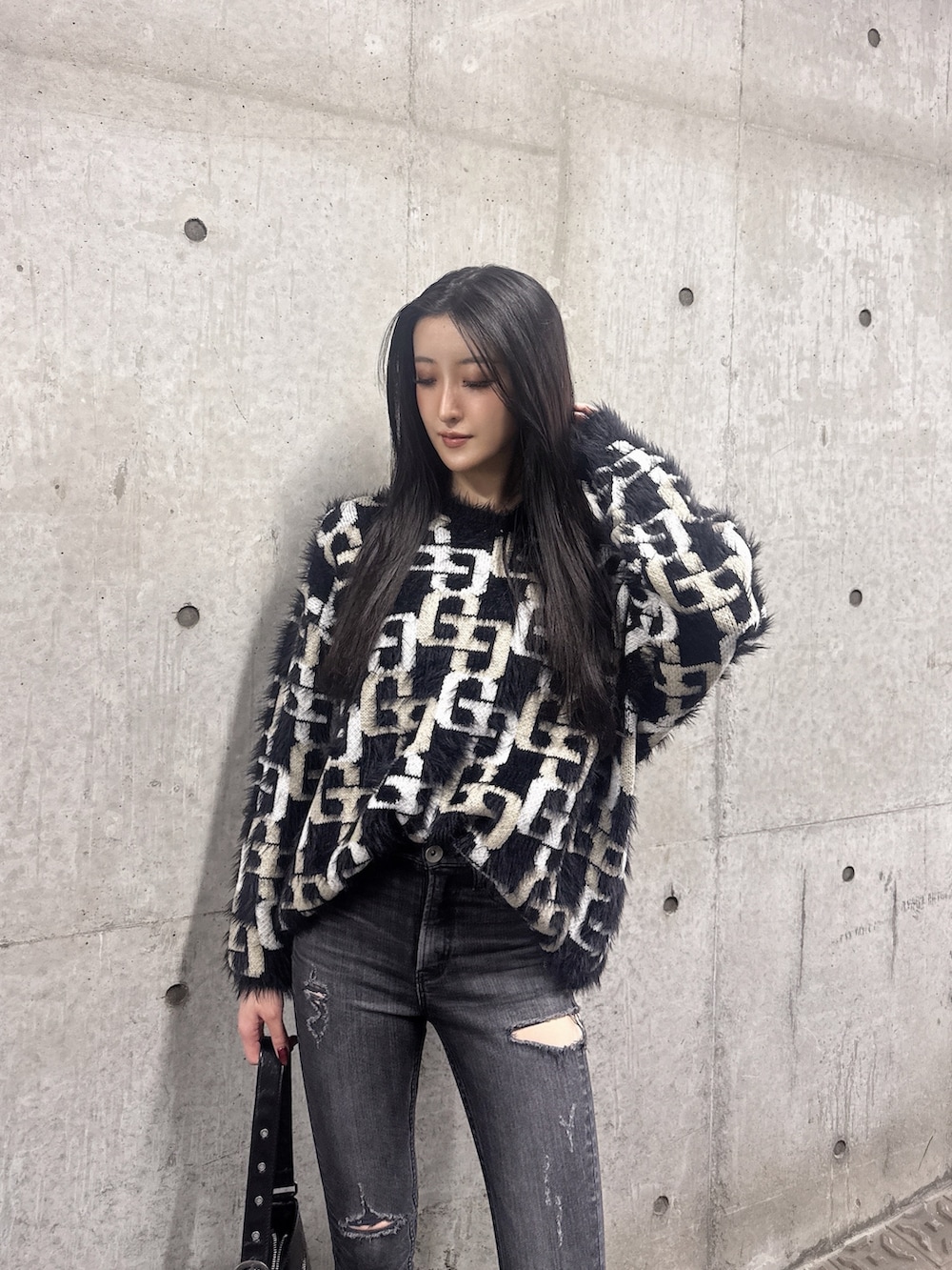 ブラック系のニット/セーター、ブラック系のデニムパンツ、ブラック系のブーツを着用したレディースの冬コーディネートの3枚目の写真