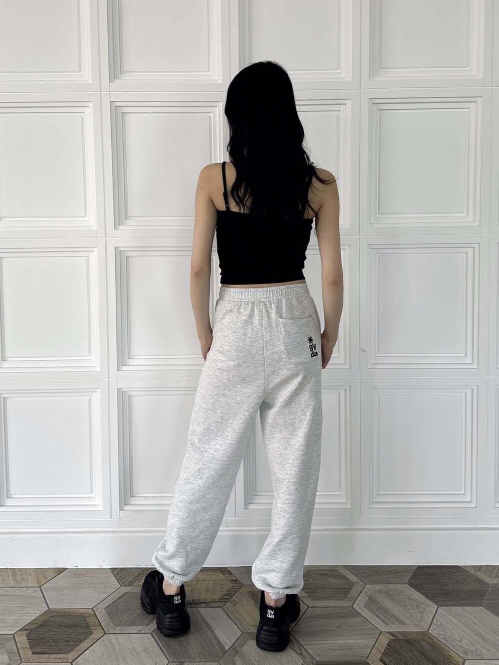 ブラック系のキャミソール、グレー系のスウェットパンツ、ブラック系のスニーカーを着用したレディースの夏コーディネートの4枚目の写真