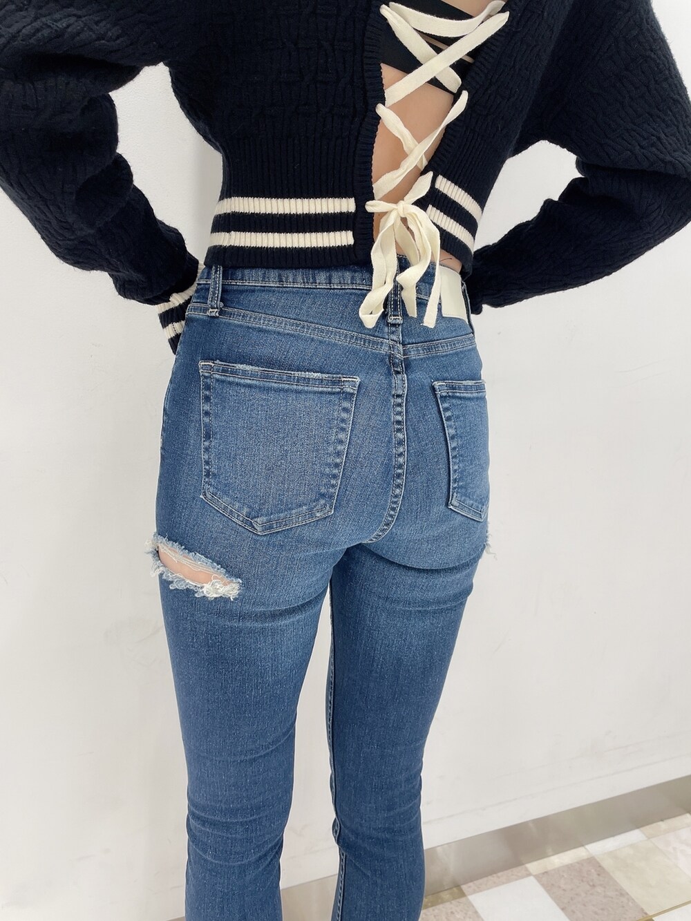 ブラック系のニット/セーター、ブルー系のデニムパンツ、ブラック系のパンプスを着用したレディースの秋コーディネートの4枚目の写真