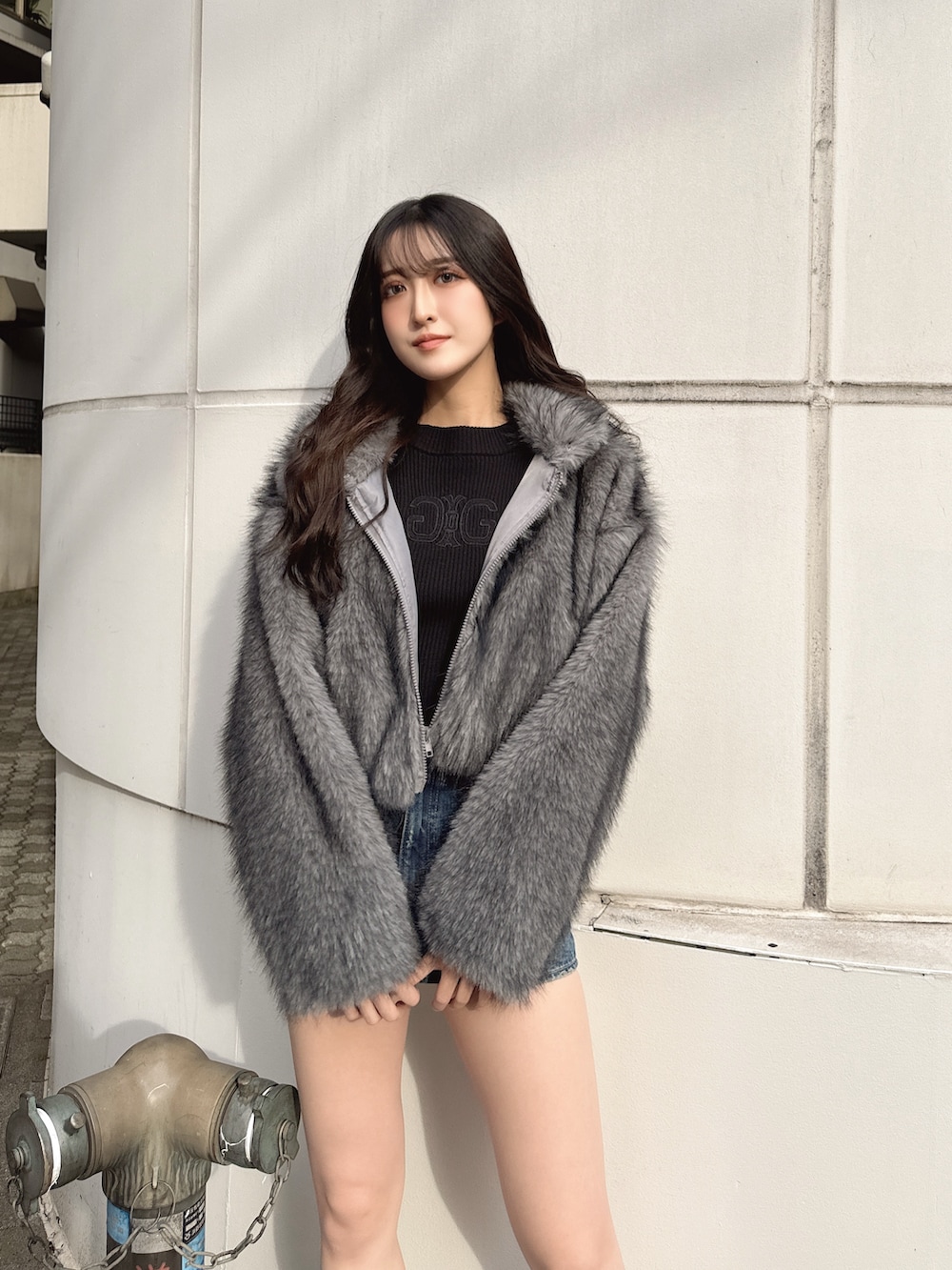 ブラック系のニット/セーター、グレー系のその他アウター、ブルー系のデニムスカートを着用したレディースの冬コーディネートの3枚目の写真