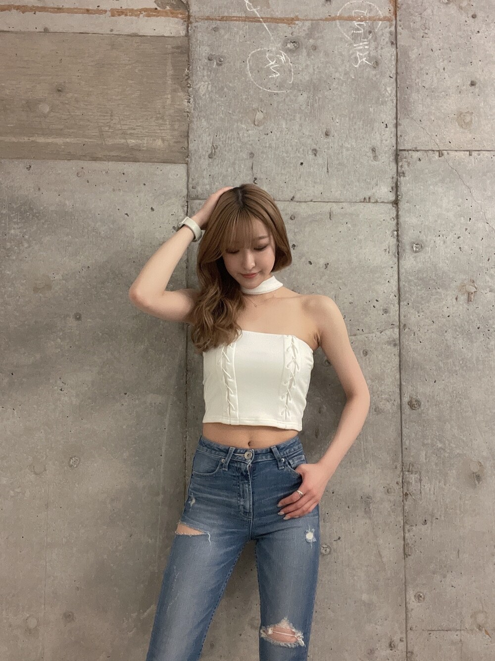 ブルー系のデニムパンツ、ホワイト系のチューブトップ、ホワイト系のパンプスを着用したレディースの春コーディネートの2枚目の写真