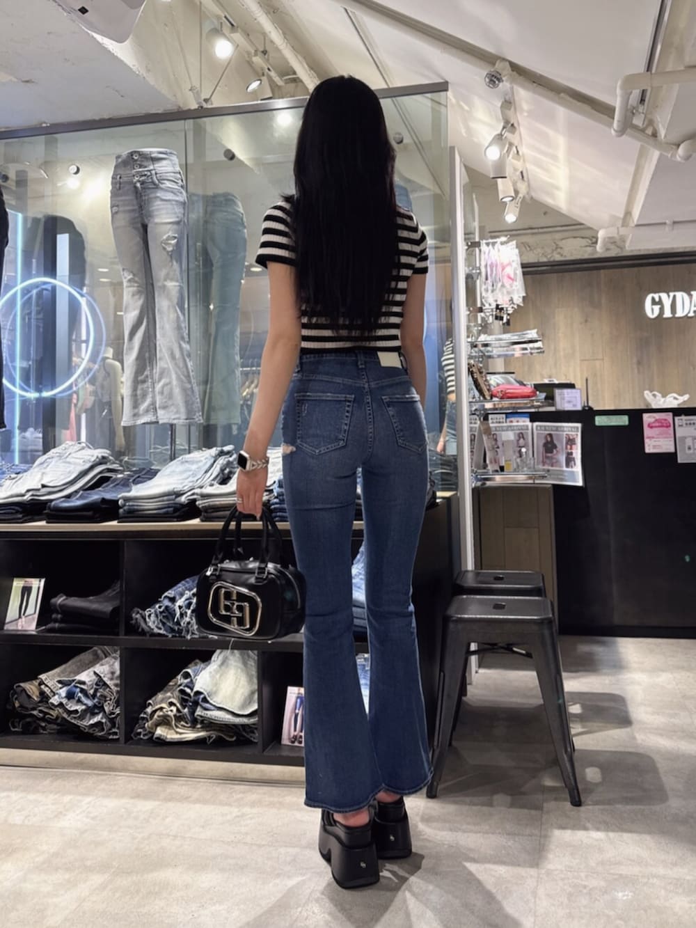 ブラック系のハンドバッグ、ブルー系のデニムパンツ、ブラック系のサンダルを着用したレディースの夏コーディネートの3枚目の写真