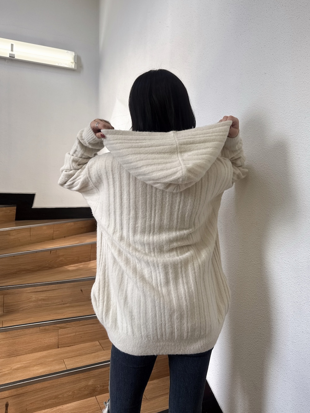 ホワイト系のワンピース、ブルー系のデニムパンツ、ブラック系のブーツを着用したレディースの秋コーディネートの4枚目の写真