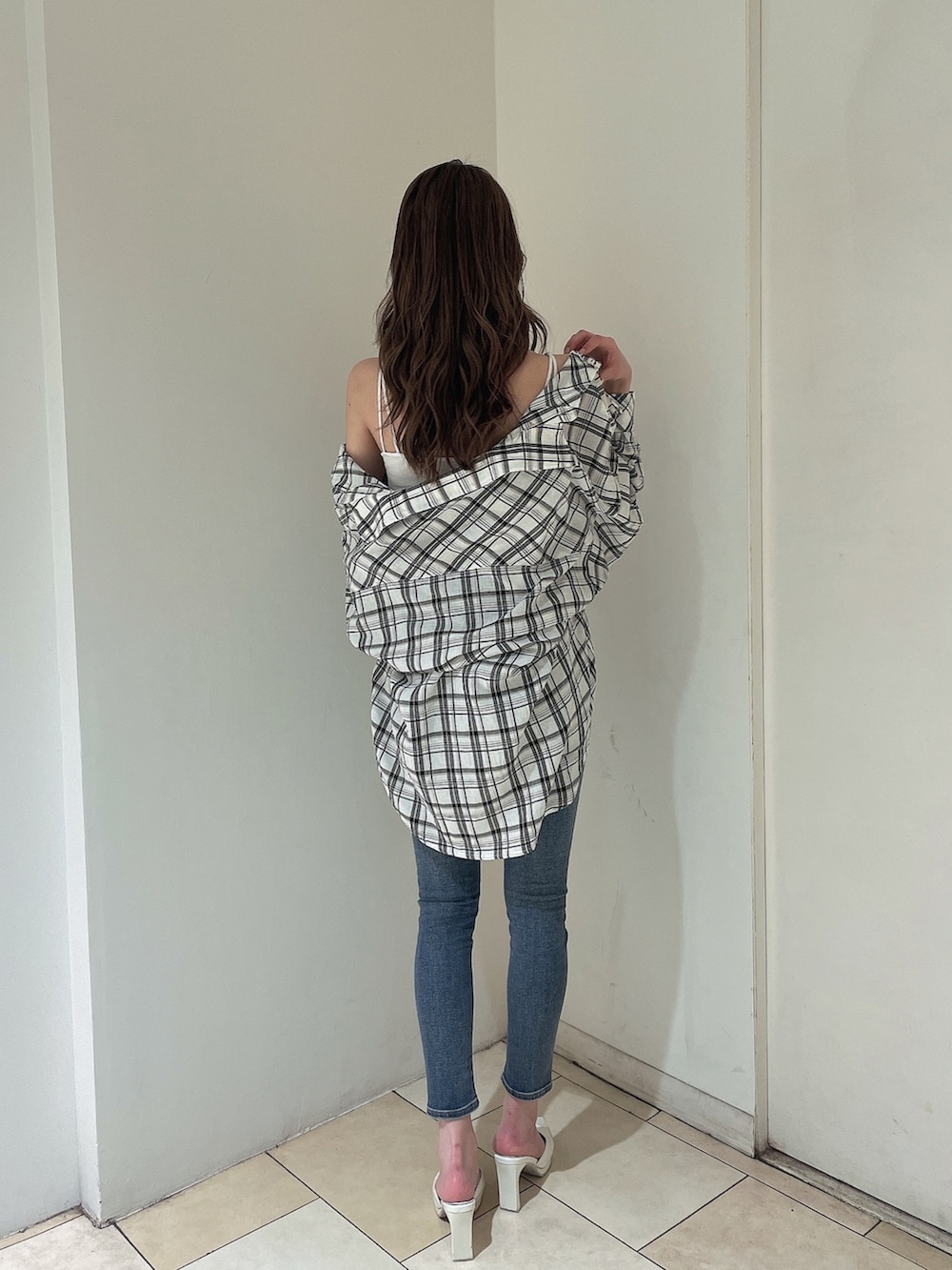 ブルー系のデニムパンツ、ホワイト系のシャツ/ブラウス、ホワイト系のキャミソールを着用したレディースの春コーディネートの2枚目の写真