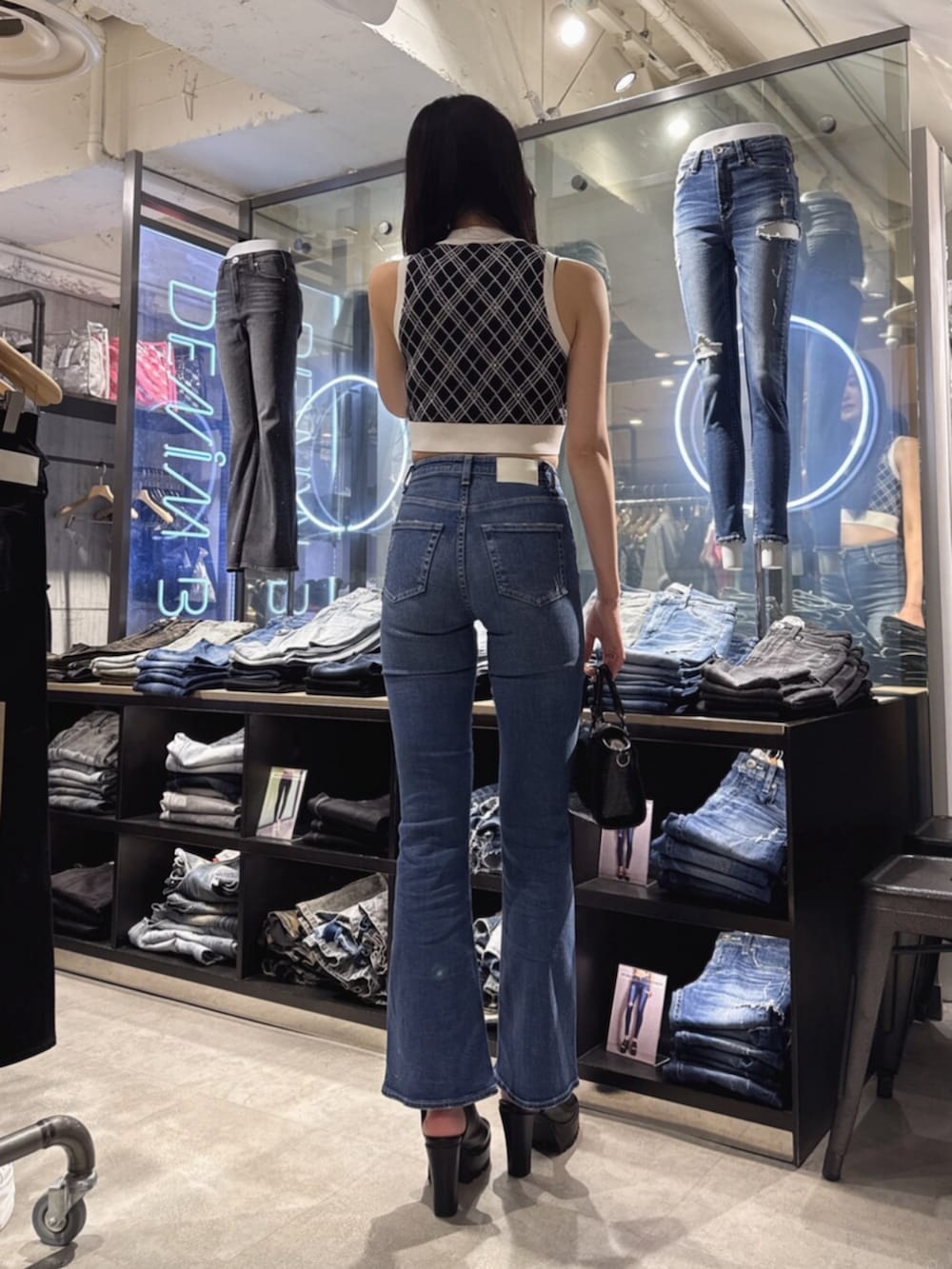 ブラック系のハンドバッグ、ブラック系のニット/セーター、ブルー系のデニムパンツを着用したレディースの夏コーディネートの3枚目の写真