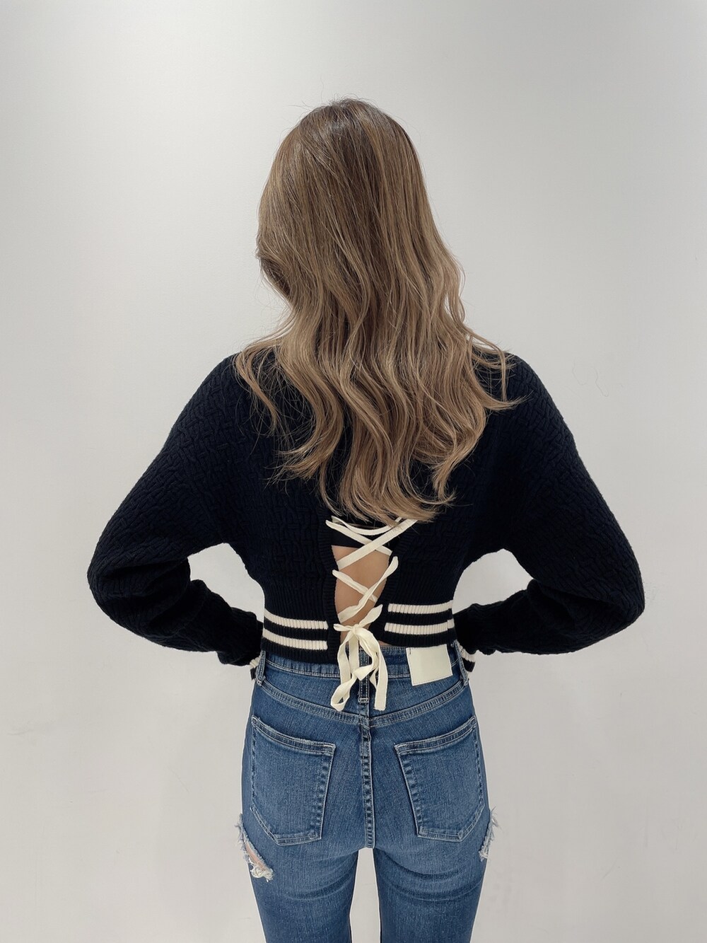 ブラック系のニット/セーター、ブルー系のデニムパンツ、ブラック系のパンプスを着用したレディースの秋コーディネートの3枚目の写真