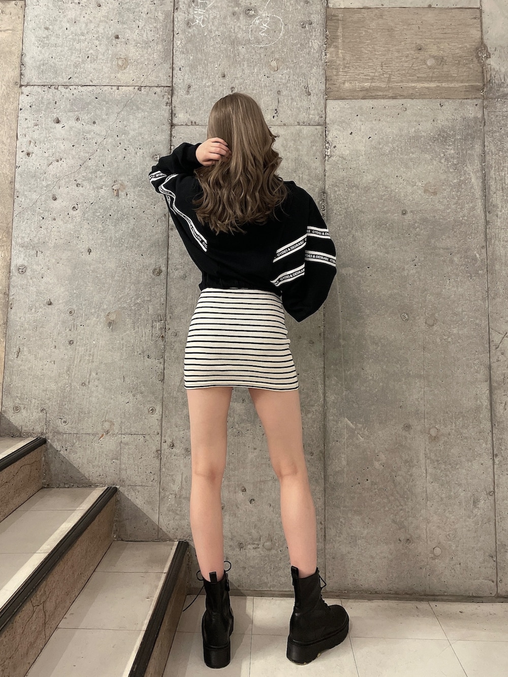 ブラック系のスウェット、ホワイト系のワンピース、ブラック系のブーツを着用したレディースの夏コーディネートの3枚目の写真