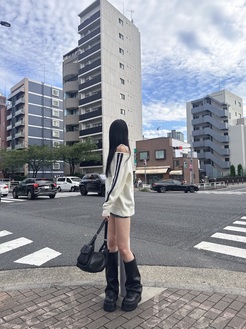 ホワイト系のニット/セーター、ブルー系のデニムスカート、ブラック系のブーツを着用したレディースの秋コーディネートの2枚目の写真