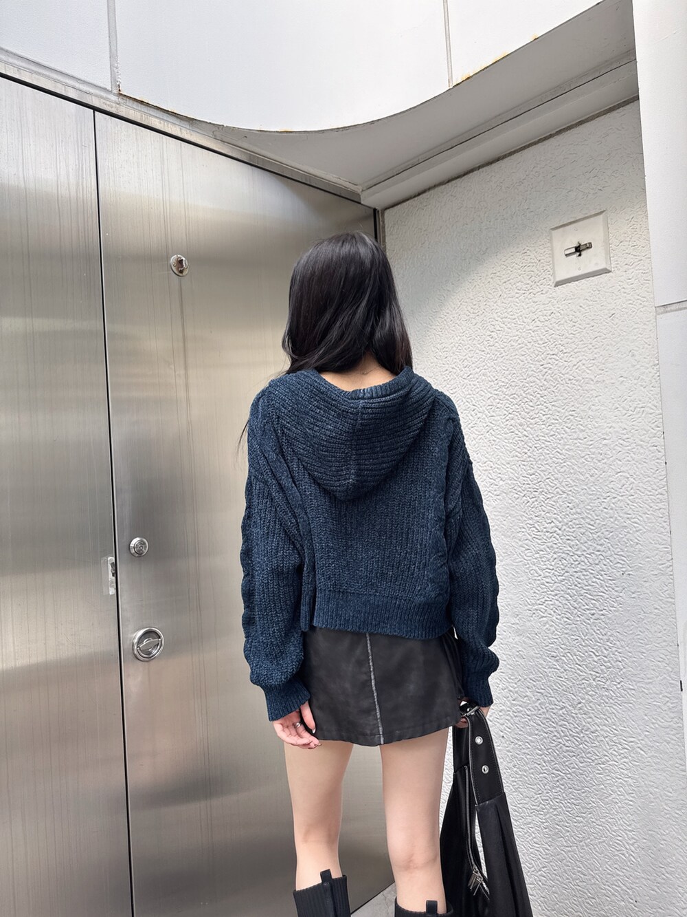 ブラック系のスカート、ブルー系のニット/セーター、ブラック系のブーツを着用したレディースの秋コーディネートの3枚目の写真