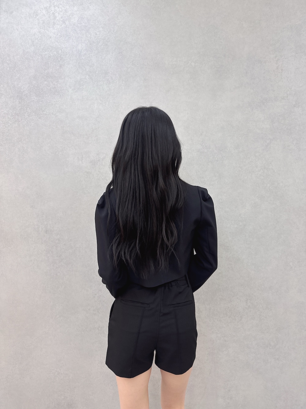 ブラック系のテーラードジャケット、ブラック系のその他パンツ、ホワイト系のキャミソールを着用したレディースの冬コーディネートの4枚目の写真