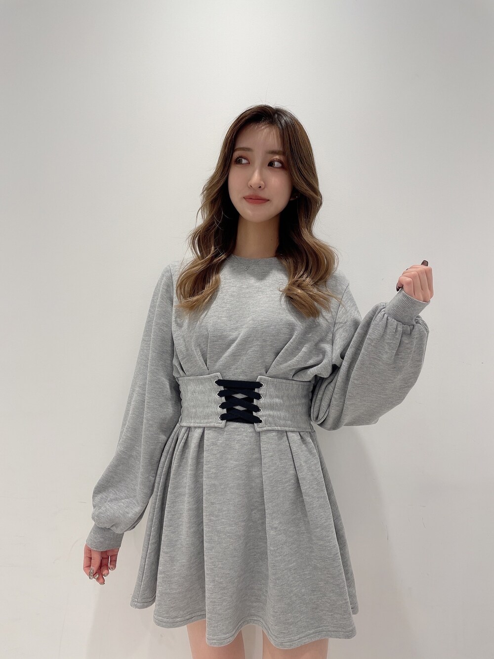 グレー系のワンピース、ブラック系のデニムパンツ、ブラック系のブーツを着用したレディースの冬コーディネートの2枚目の写真