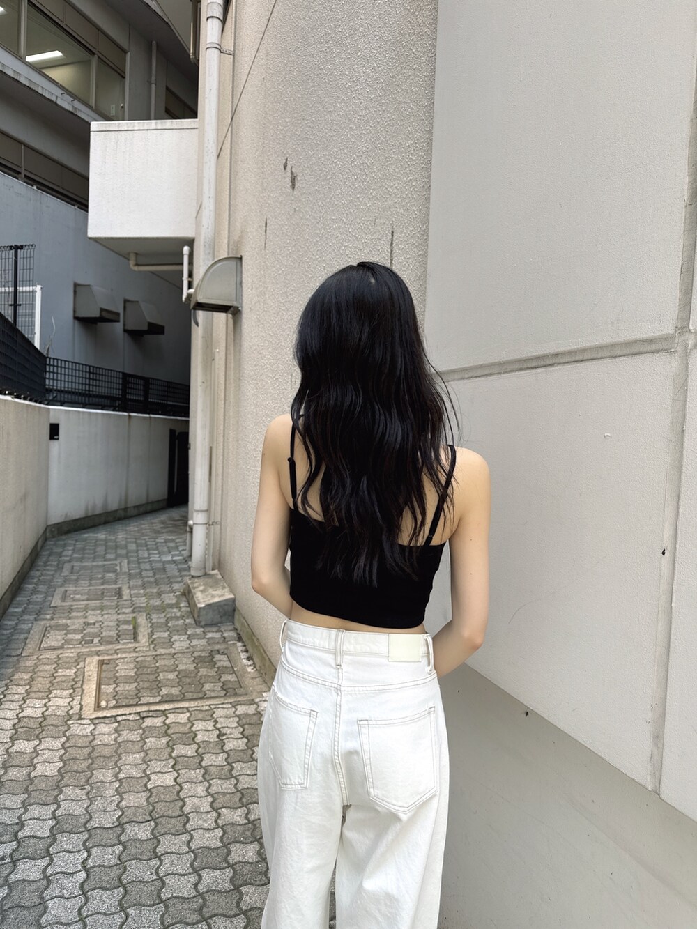 ホワイト系のデニムパンツ、ブラック系のキャミソール、ブラック系のサンダルを着用したレディースの夏コーディネートの2枚目の写真