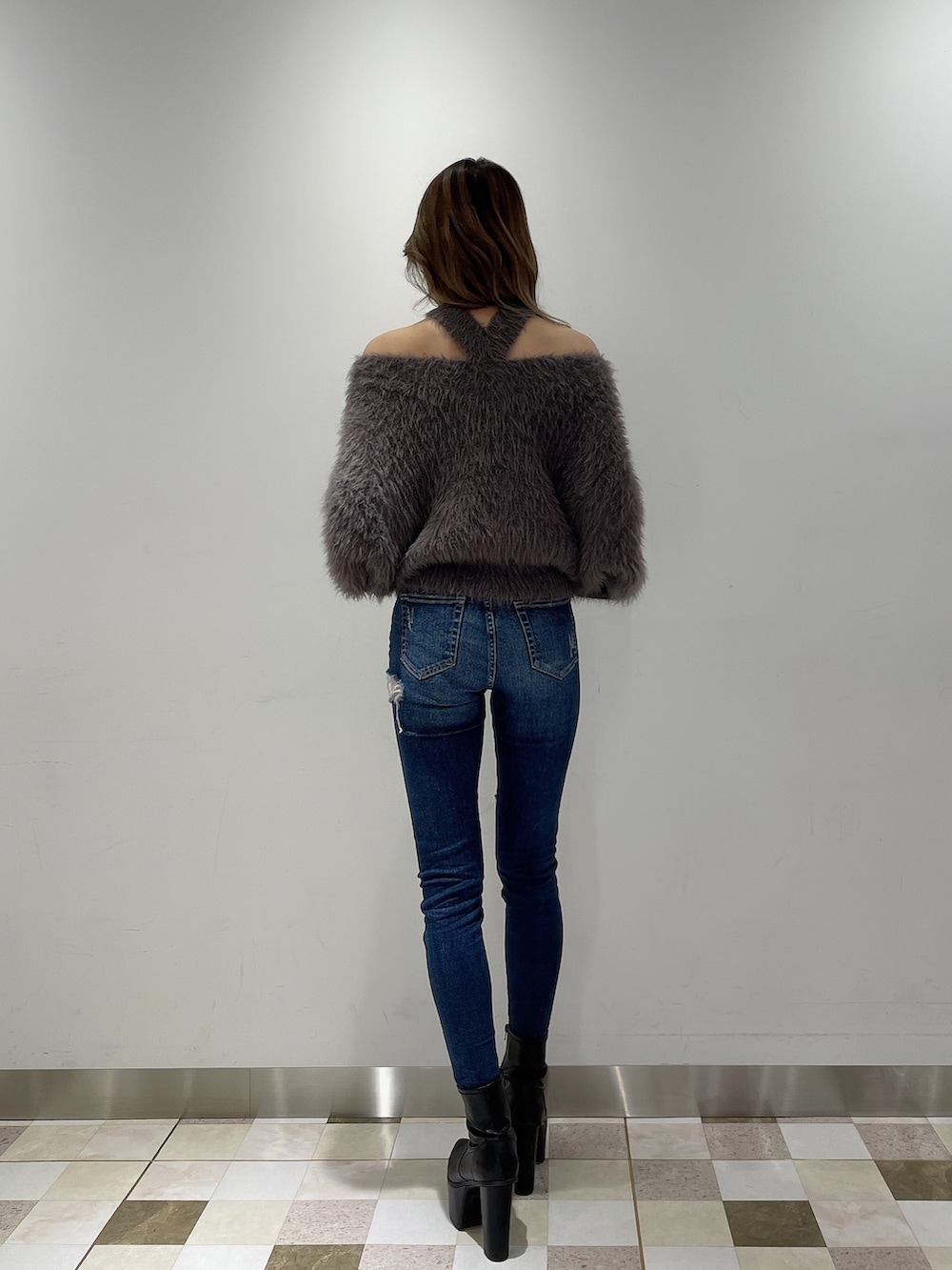 ブルー系のデニムパンツ、グレー系のニット/セーター、ブラック系のブーツを着用したレディースの冬コーディネートの2枚目の写真