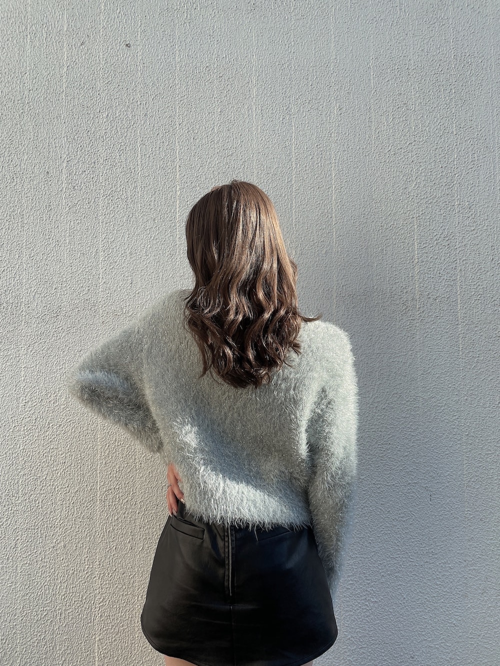 グレー系のニット/セーター、ブラック系のブーツ、ブラック系のスカートを着用したレディースの秋コーディネートの4枚目の写真