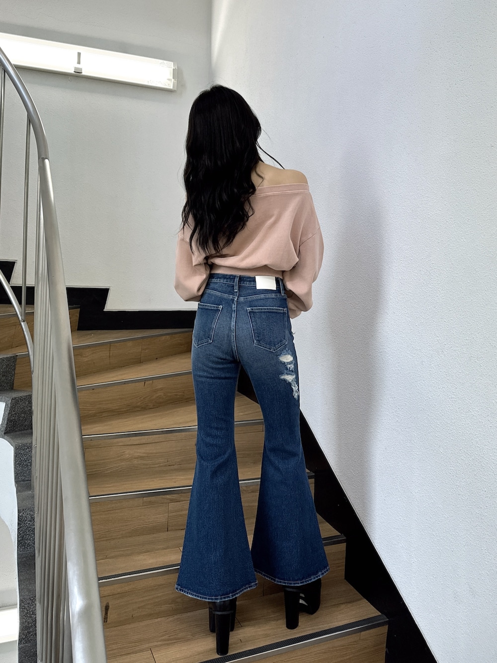 ピンク系のスウェット、ブルー系のデニムパンツ、ブラック系のブーツを着用したレディースの夏コーディネートの2枚目の写真