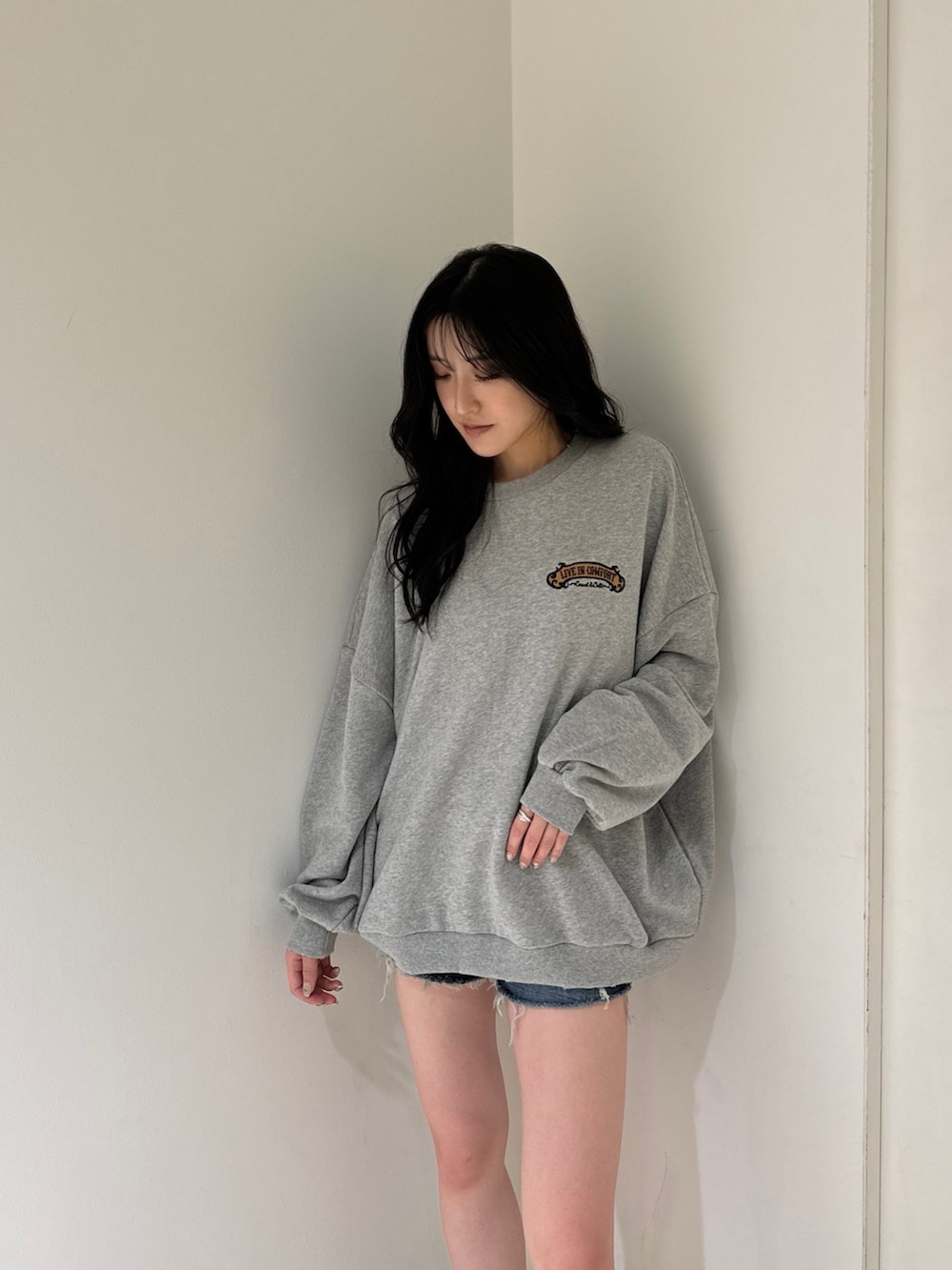 グレー系のスウェット、ブルー系のデニムパンツ、ベージュ系のスリッポンを着用したレディースの夏コーディネートの3枚目の写真