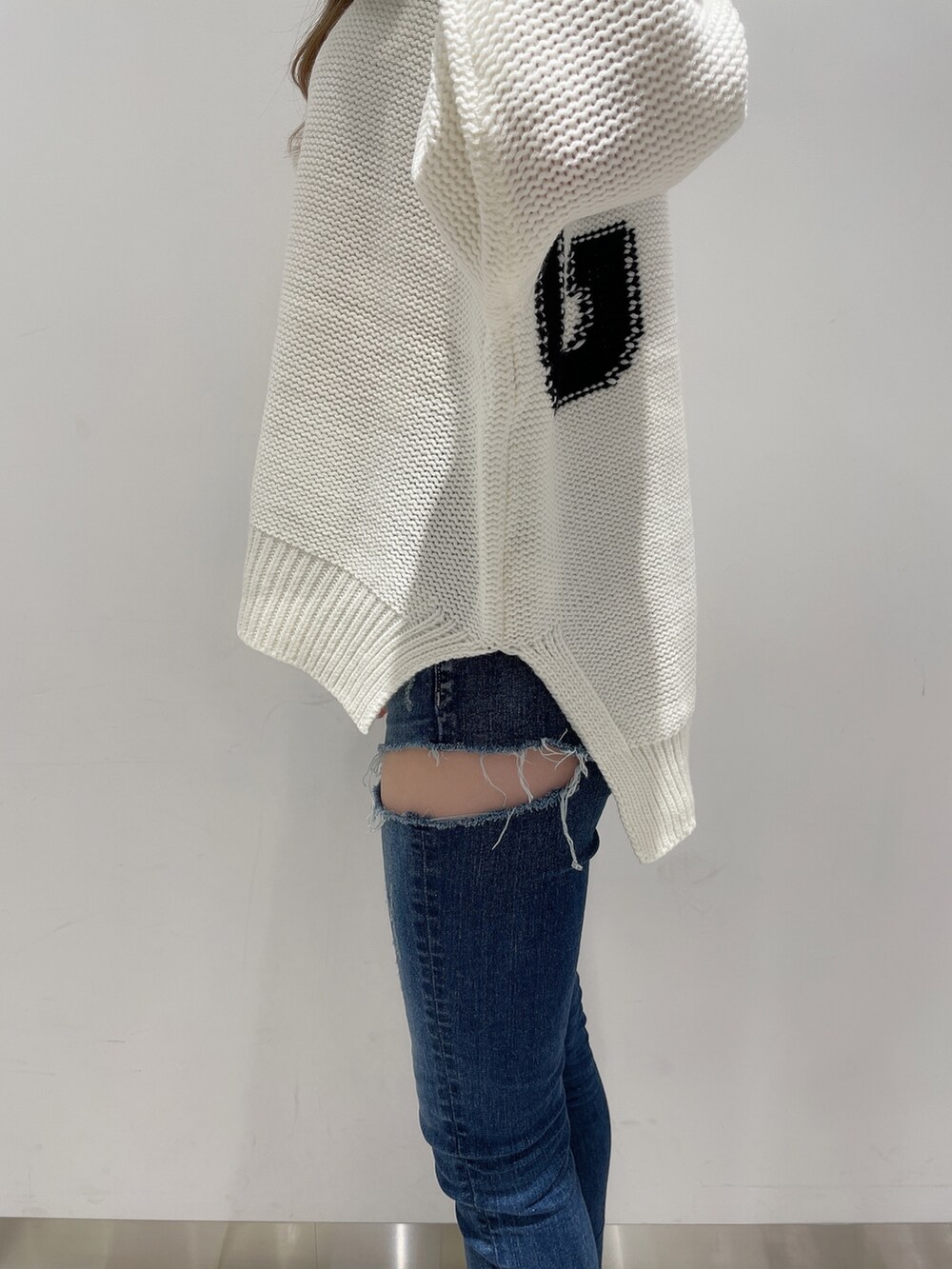 ホワイト系のニット/セーター、ブルー系のデニムパンツ、ブラック系のブーツを着用したレディースの冬コーディネートの5枚目の写真