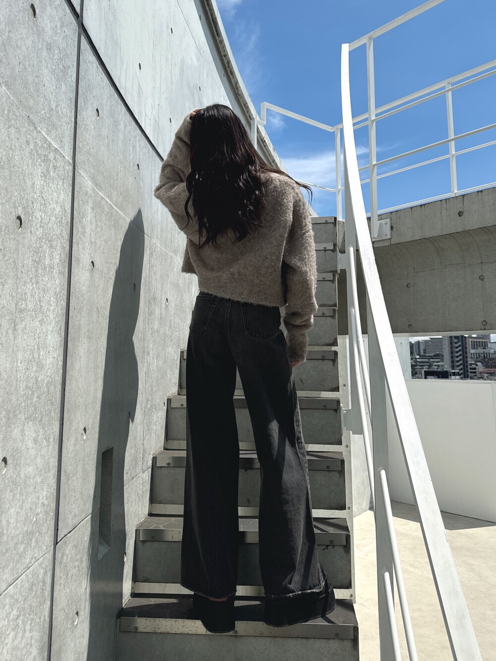 ブラック系のデニムパンツ、ブラック系のスリッポン、ベージュ系のカーディガン/ボレロを着用したレディースの秋コーディネートの2枚目の写真