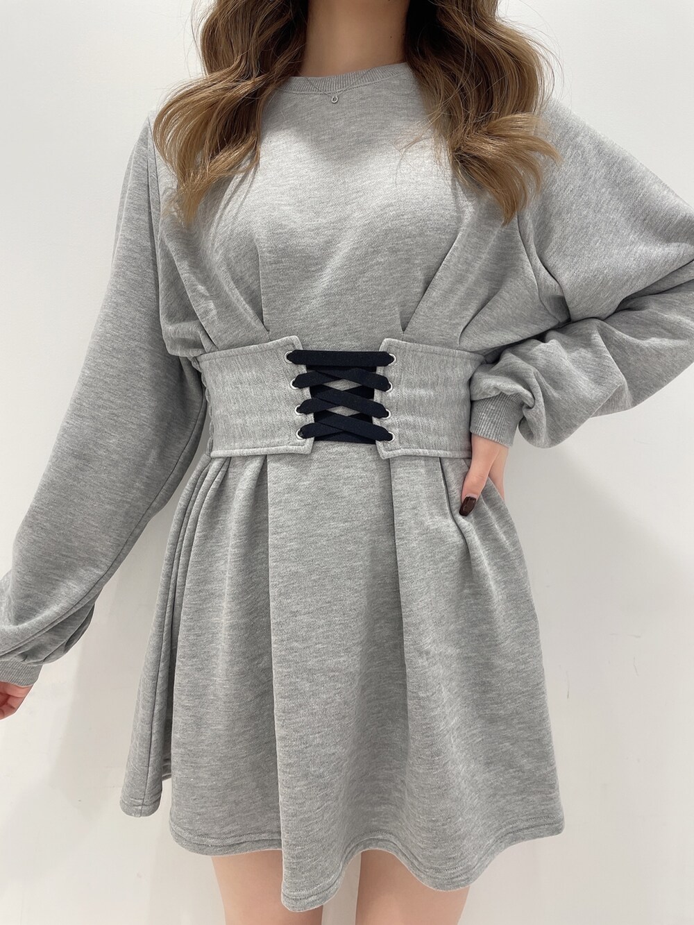 グレー系のワンピース、ブラック系のデニムパンツ、ブラック系のブーツを着用したレディースの冬コーディネートの4枚目の写真