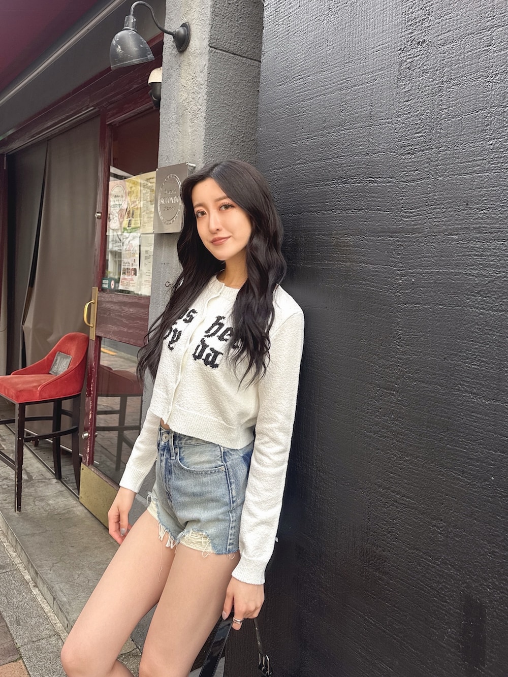 ブルー系のデニムパンツ、ブラック系のブーツ、ホワイト系のカーディガン/ボレロを着用したレディースの春コーディネートの2枚目の写真