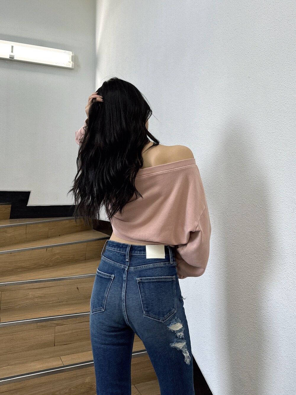 ピンク系のスウェット、ブルー系のデニムパンツ、ブラック系のブーツを着用したレディースの夏コーディネートの4枚目の写真