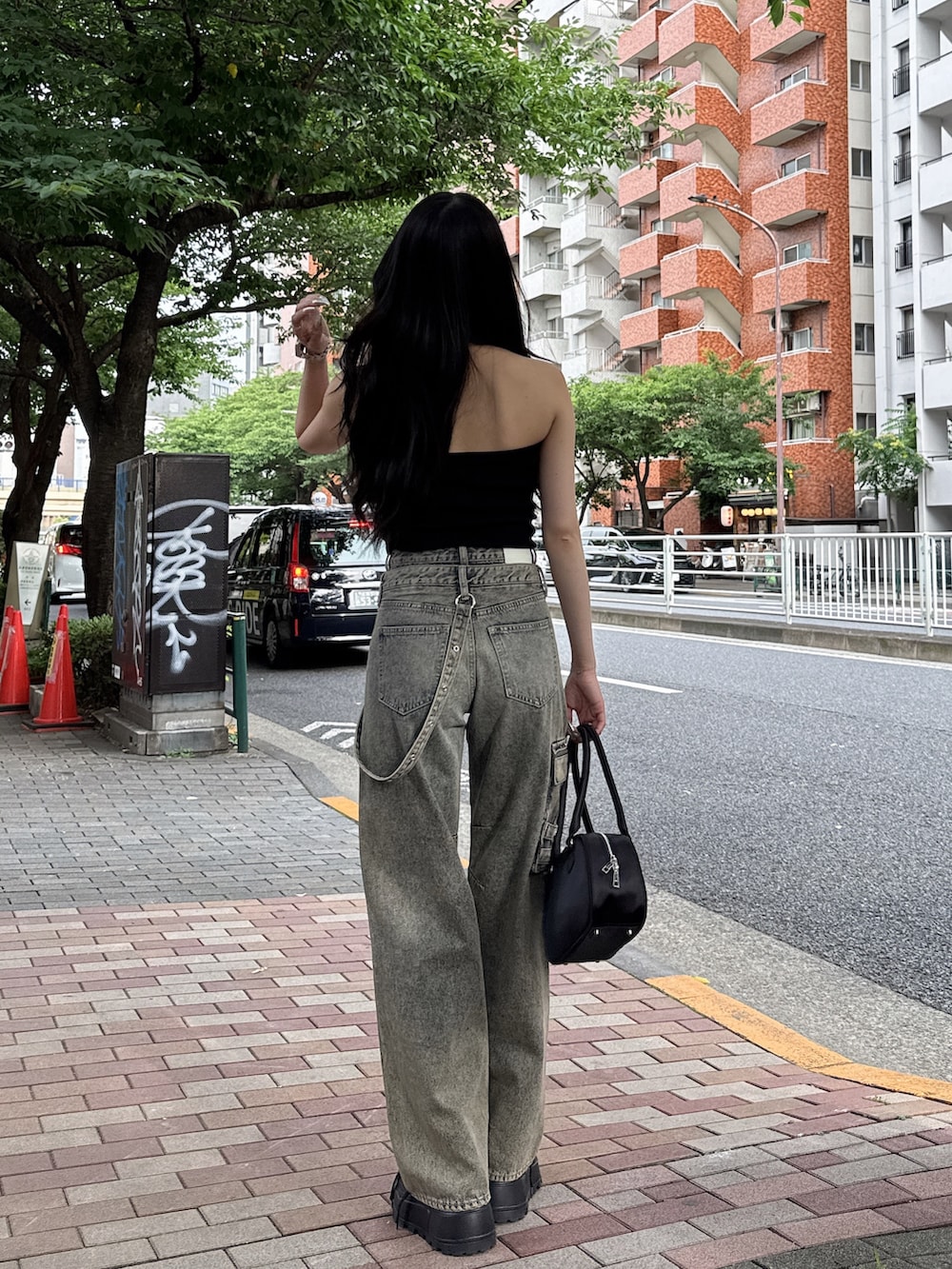 ブルー系のデニムパンツ、ブラック系のキャミソール、ブラック系のスニーカーを着用したレディースの夏コーディネートの3枚目の写真