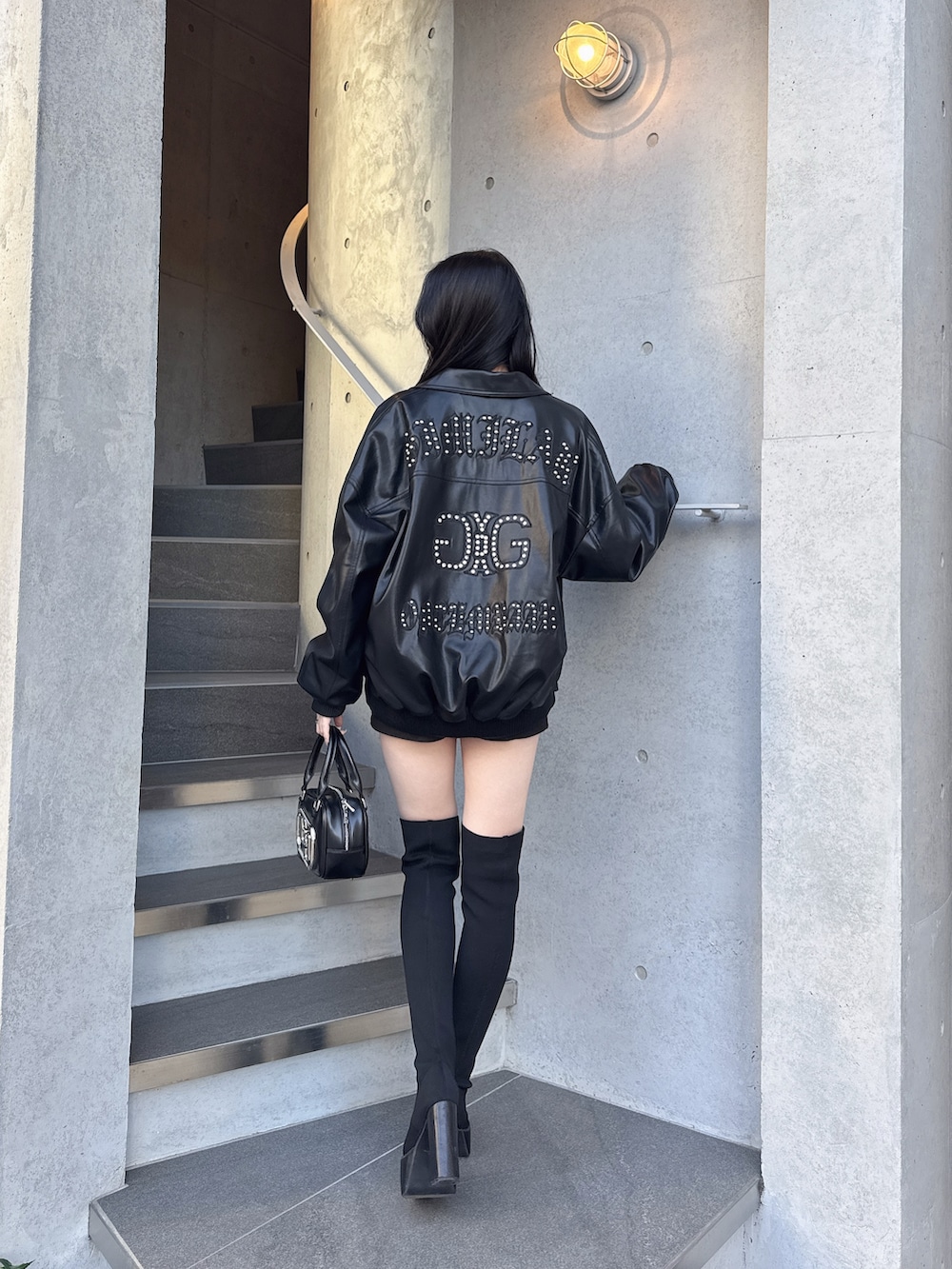 ブラック系のブルゾン、ブラック系のブーツ、ホワイト系のスウェットを着用したレディースの冬コーディネートの3枚目の写真